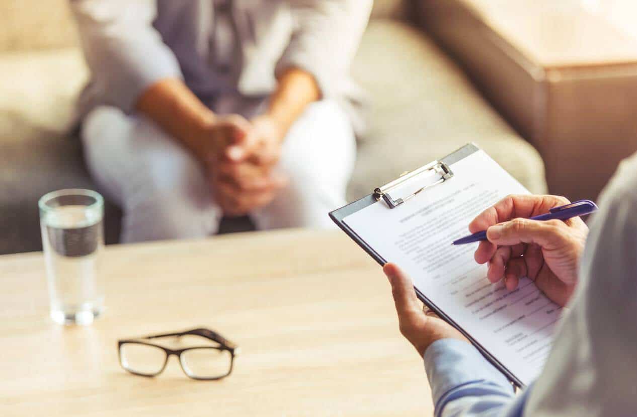 Pessoa em sessão de psicoterapia, de mãos entrelaçadas