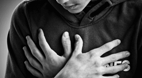 Pessoa com as duas mãos sobre o peito